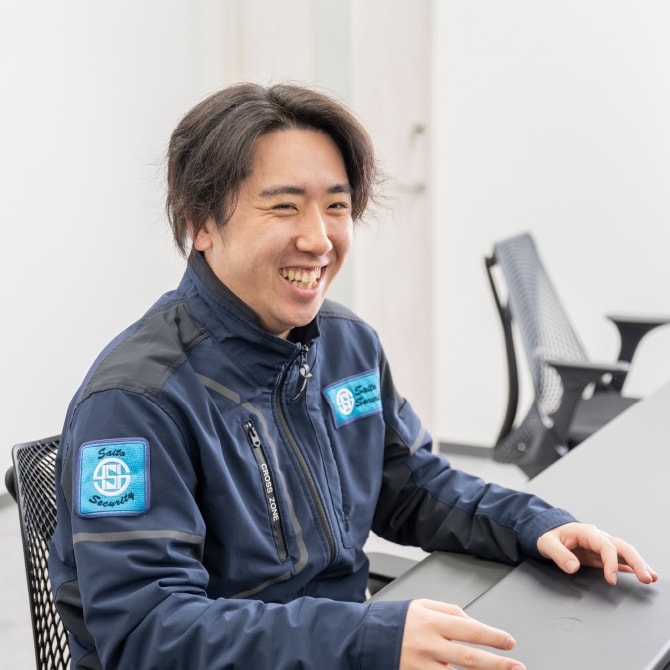 事務所で笑顔で受け答えをする作業着姿の男性社員