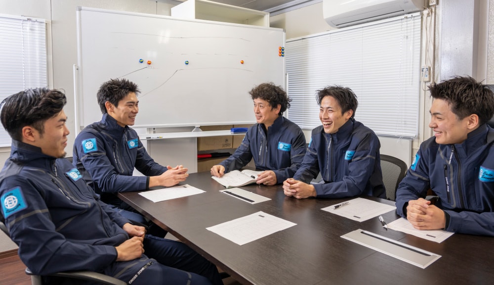 会議室で資料を囲み和やかに話し合う社員たち