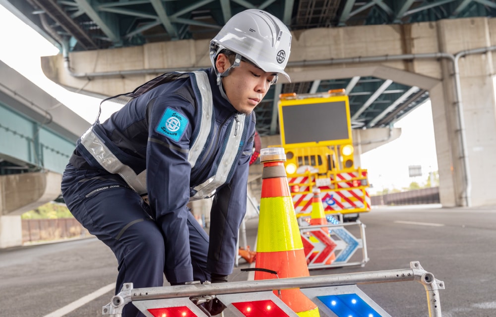 高架下でカラーコーンや矢印板を設置する様子